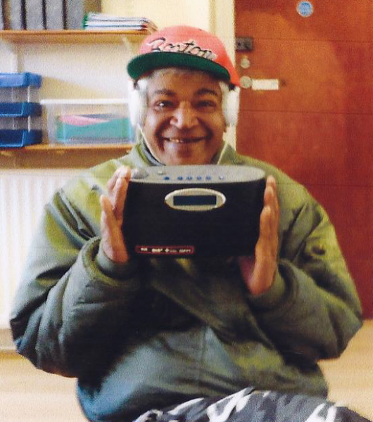Donate - an older homeless lady smiles as she holds her new radio