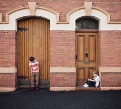 Young people - two boys stand apart against a brick wall